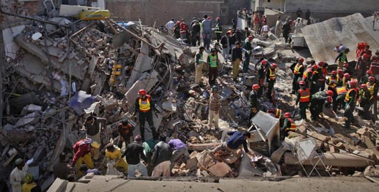 Residents and rescue workers go through the rubble of a three-story factory building, which collapsed in Lahore