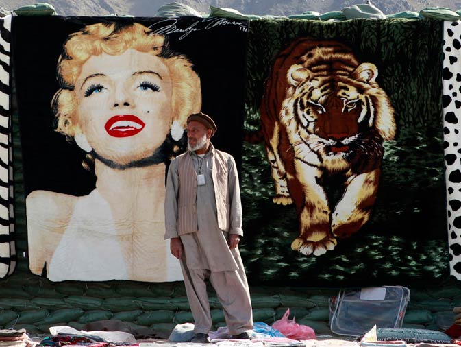 An Afghan vendor waits for customers in front of a blanket with an image of late Hollywood actress Marilyn Monroe at a bazaar in Forward Operating Base Joyce in Kunar province, eastern Afghanistan. ? Reuters Photo
