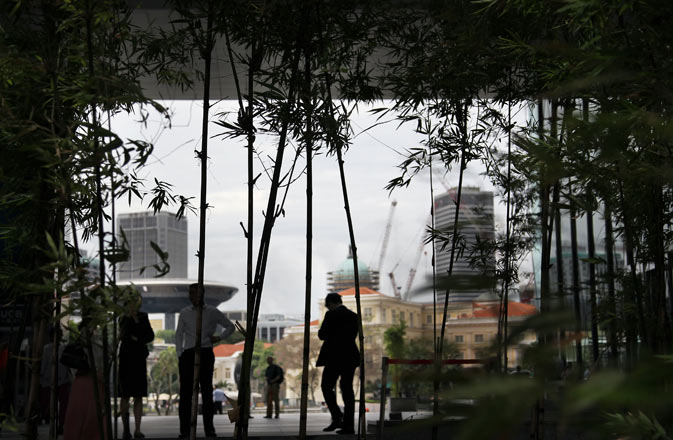 Office workers are silhouetted against the Singapore River during lunch hour in the business district of Singapore. ? AP Photo