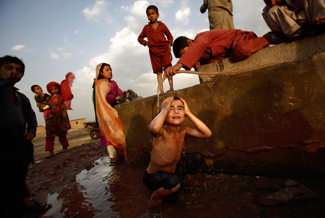 An Afghan refugee boy pours water on Doost Hamid, 7, bottom center, while bathing at a water point in a slum area on the outskirts of Islamabad. People in Pakistan are facing shortage of water due to the low level of water in the country's dams, according to Pakistani Meteorological Department. ? Photo by AP