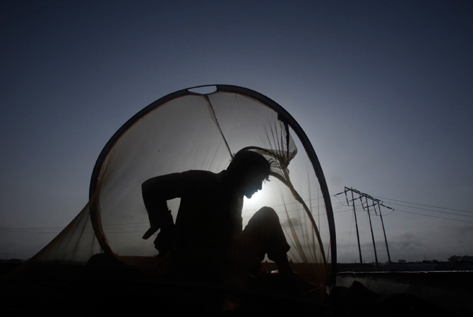 A man is silhouetted against the sun as he sits in a mosquito net early morning atop of a tanker, which was used to carry fuel for NATO forces in Afghanistan, parked at a compound in Karachi. ? Photo by Reuters