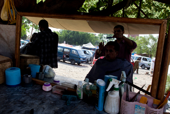 Pakistani customers have their hair cut at a roadside shop in Islamabad. ? Photo by AP
