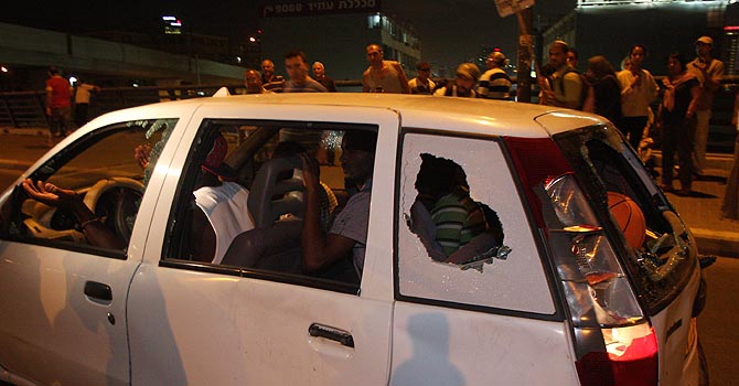 ISRAEL-IMMIGRATION-AFRICA-RACISM-DEMO African immigrants drive a car whose windows were shattered by Israeli protesters taking part in a rally against the government's handling of the flow of African migrants into Israel, in Tel Aviv on May 23, 2012. AFP PHOTO/RONI SCHUTZER == ISRAEL OUT ==