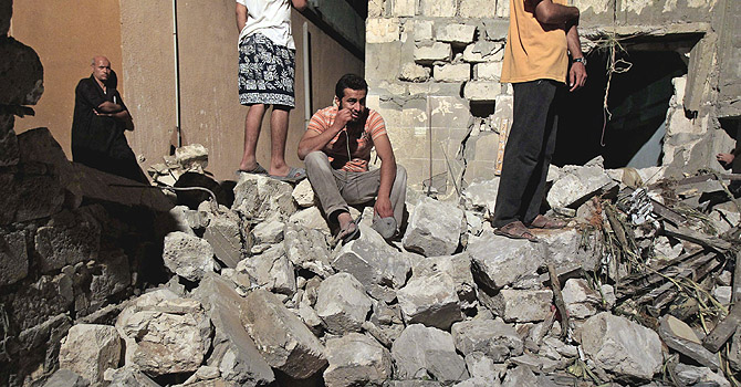 Mideast Libya Civilian Casualties FILE - In a June 19, 2011, file photo made on a government-organized tour, a Libyan man sits on debris from a damaged residential building on the outskirts of Tripoli, Libya. Human Rights Watch is calling on NATO to provide compensation for Libyans who lost loved ones or had property damaged in airstrikes during the bombing campaign that helped rebels oust former leader Moammar Gadhafi. (AP Photo/Ivan Sekretarev, File)