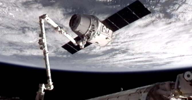 spacex-dock-nasa-ap_670 image provided by NASA-TV shows the SpaceX Dragon commercial cargo craft, top, after Dragon was grappled by the Canadarm2 robotic arm and connected to the International Space Station. – Photo by AP
