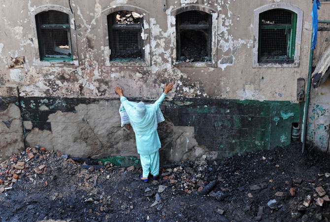 A Kashmiri Muslim woman grieves as unseen fire services personnel and volunteers clear debris from the charred remains of the shrine.