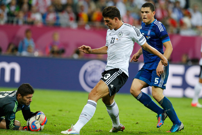 Greece's Kyriakos Papadopoulos (Right) looks on as goalkeeper Michalis Sifakis (Left) makes a save after Germany's Mario Gomez attempt a shot on goal during their Euro 2012 quarter-final.