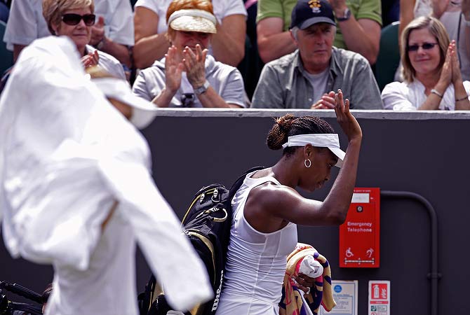 Venus Williams of the United States, right, gestures as she leaves after she was defeated by Elena Vesnina of Russia, foreground left, following a first round women's singles match at the All England Lawn Tennis Championships at Wimbledon, England, Monday, June 25, 2012. ? AP Photo