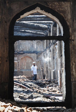 A Kashmiri Muslim volunteer looks on as he helps clear debris inside the charred remains of the shrine.