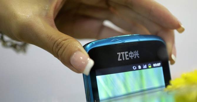 ZTE A model takes a ZTE V882 waterproof smartphone out of an aquarium at the company's exhibition pavilion during the CommunicAsia information and communications technology trade show in Singapore. – Reuters