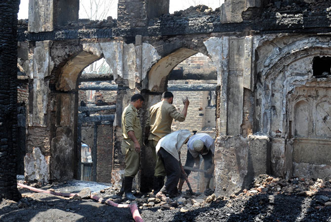 Fire services personnel and volunteers clear debris inside the charred remains of the 200-year old shrine.