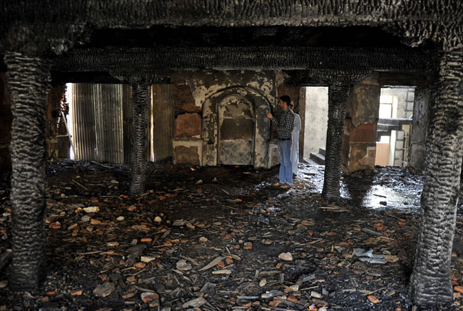 A Kashmiri Muslim looks on inside the charred remains of the 200-year old shrine of Sheikh Abdul Qadir Jeelani.