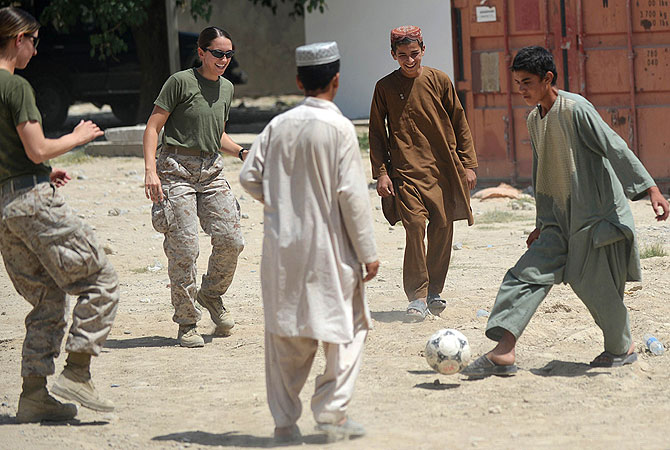 US Marine Cpl. Reagan Odhner (L) assigned in Female Engagement Team (FET) and US Navy Lt. Sarah Pilewski (2L) from 1st Battalion 7th Marines Regiment play football with Afghan children at Forward Operating Base (FOB) Jackson also known as Sabit Khadam. -Photo by AFP
