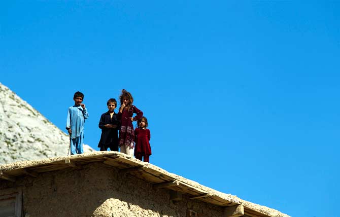 Afghan children stand on a rooftop to watch soldiers from 3rd Platoon, Dagger Company of the 2nd Battalion, 12th Infantry Regiment during a patrol through the village of Sandray in the Pech River Valley of Afghanistan's Kunar Province. ? Photo by AFP