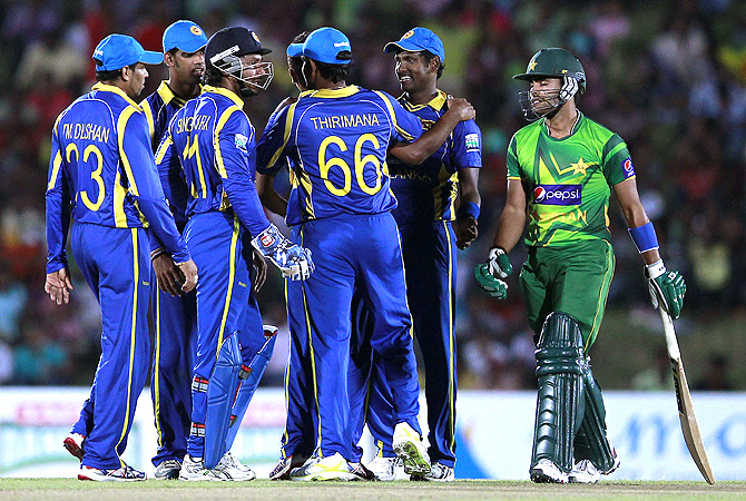 Pakistan's Umar Akmal walks off the field after his dismissal as Sri Lanka's team celebrate. -Photo by Reuters