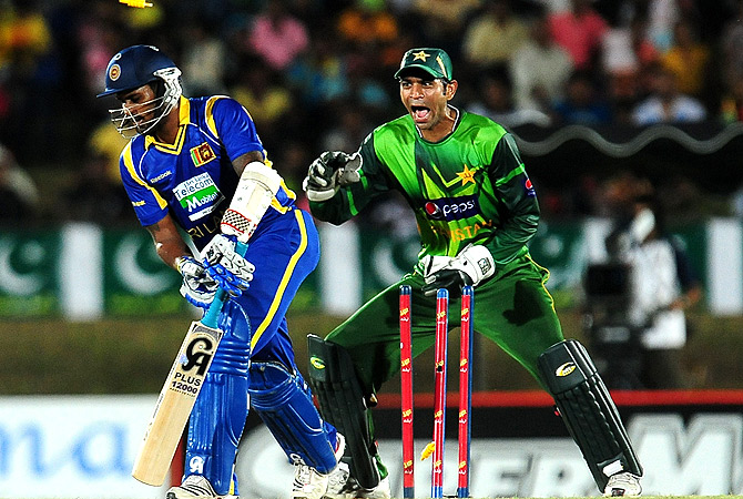 Sri Lankan cricketer Chamara Kapugedera (L) gets dismissed by unseen Pakistan cricketer Shahid Afridi as wicketkeeper Shakeel Ansar looks on. -Photo by AFP