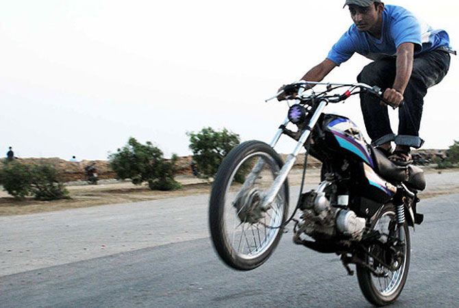 A young man performs impromptu bike stunts at a deserted road in Karachi, Pakistan.