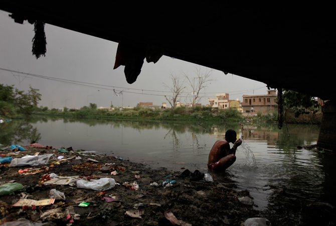 An Indian man bathes in a polluted channel under a bridge in Amritsar. ? Photo by AP