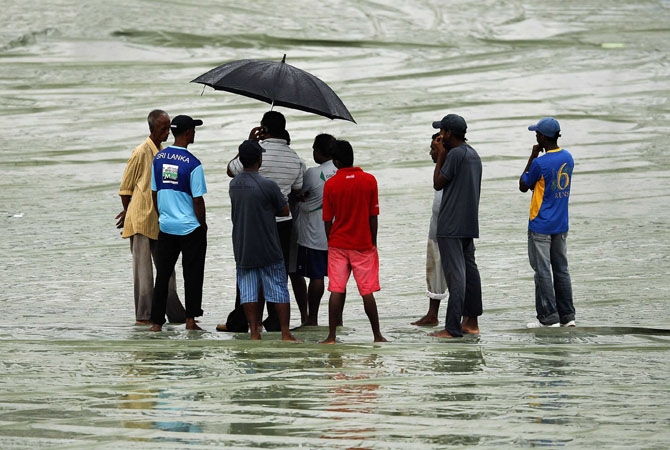 Ground workers stand on covers as the match was called off for the day due to rain, during the second day of second test match between Sri Lanka and Pakistan in Colombo July 1, 2012. ? Photo AFP