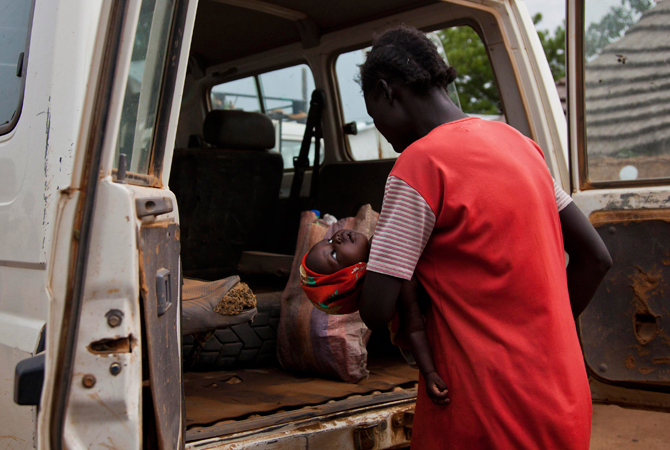 A woman carrying her sick child climbs into an International Rescue Committee (IRC) vehicle to travel to the Aweil State Hospital in Aweil from the Malualkon Primary Health Care Center in Malualkon, in the South Sudanese state of Northern Bahr el Ghazal. – Photo by Reuters