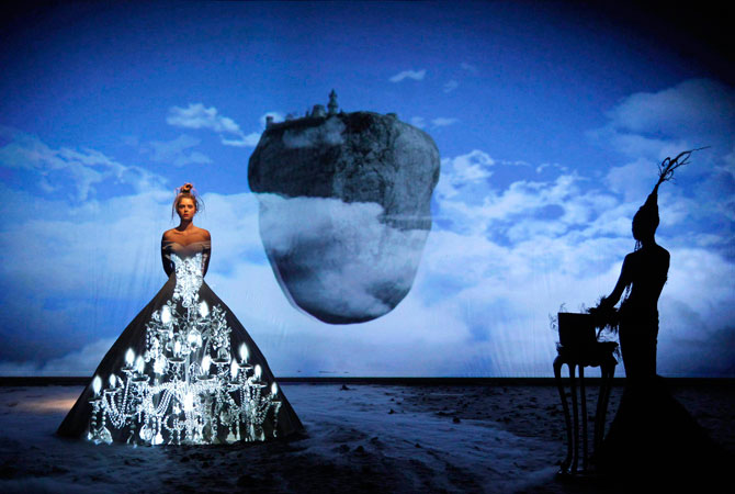 Setting the scene, a candle chandelier flickers on the princess' gown, before a surrealist image of a castle perched on a rock in the sky. ? Photo by Reuters
