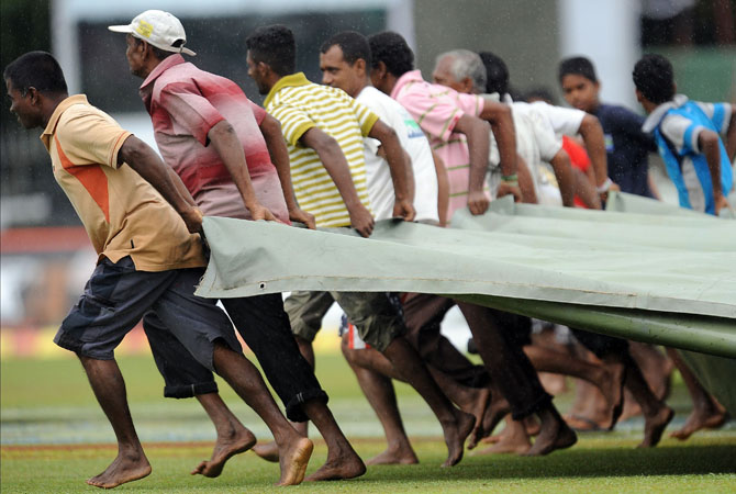 Sri Lankan ground staff pull a tarp over the grounds as rain stops play during the second day of the second Test match between Sri Lanka and Pakistan at the Sinhalese Sports Club (SSC) in Colombo on July 1, 2012. ? Photo AFP