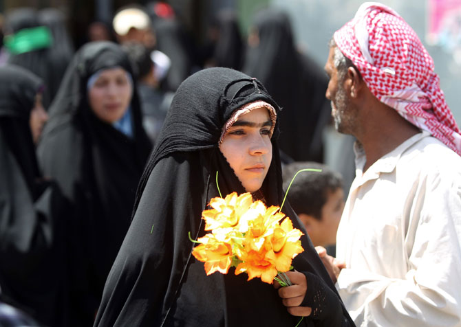 A Shiite pilgrim holds flowers in her hands as she tours the Imam Hussein shrine in the central Iraqi holy city of Karbala on July 5, 2012. The grandson of Islam's Prophet Mohammed is revered by Shiite Muslims across the world. ? Photo by AFP