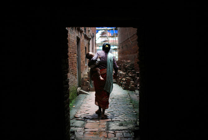 A woman carries a sleeping child as she walks through a small alley in the ancient city of Bhaktapur. ? Photo by Reuters