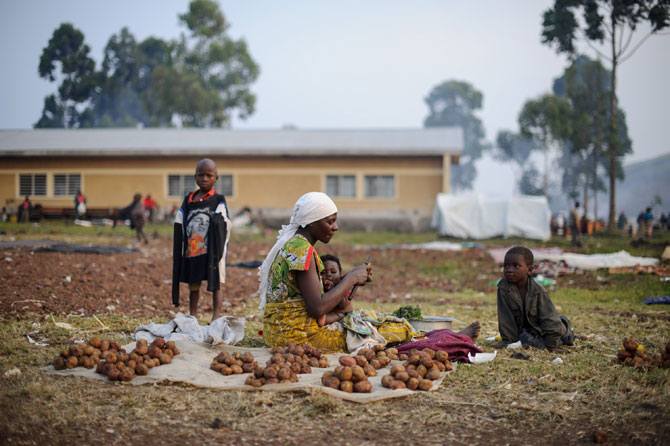A displaced Congolese woman from Rugari sits peeling potatoes at a small stall she has set up in the Kanyarucinya primary school in Kibati district on the outskirts of Goma in the east of the Democratic Republic of the Congo on July 30, 2012. According to Prudent Mutarutwa, the secretary of the displaced camp here, over 11,000 people have come to Kanyarucinya in the past week, with over 20,000 people in Kabati district, fleeing fighting between the government army and M23 rebels in the area around Kibumba and Rugar