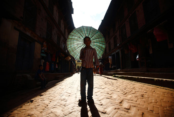 A boy with his umbrella arrives to participate for the Ghantakarna festival at the ancient city of Bhaktapur. According to legend, the demon is believed to 'steal? children and women from their homes and localities. ? Photo by Reuters
