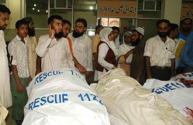 Mourners stand next to the bodies of relatives who were killed in an attack.? Photo by AFP