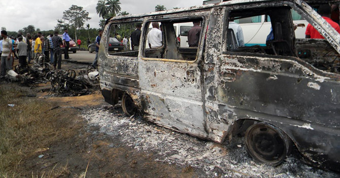 People-gather-next-to-a-burnt-minibus-after-a-Nigerian-petrol-tanker-tipped-over-and-pools-of-spilled-oil-caught-fire670 People gather next to a burnt minibus after a Nigerian petrol tanker tipped over and pools of spilled oil caught fire.—AFP Photo