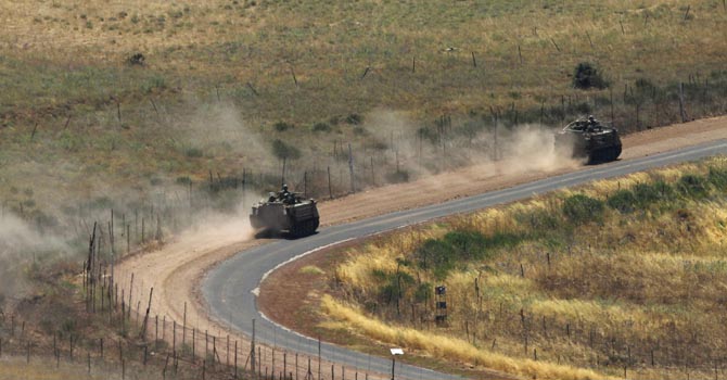 Israeli APCs drive along Israeli-Syrian border near Druze village of Buqata in the Golan Heights