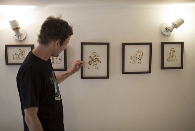 Fernando de la Rocque stands in front of some of their pieces of art at the La Cucharacha, a small alternative gallery in the stylish, in Rio de Janeiro.