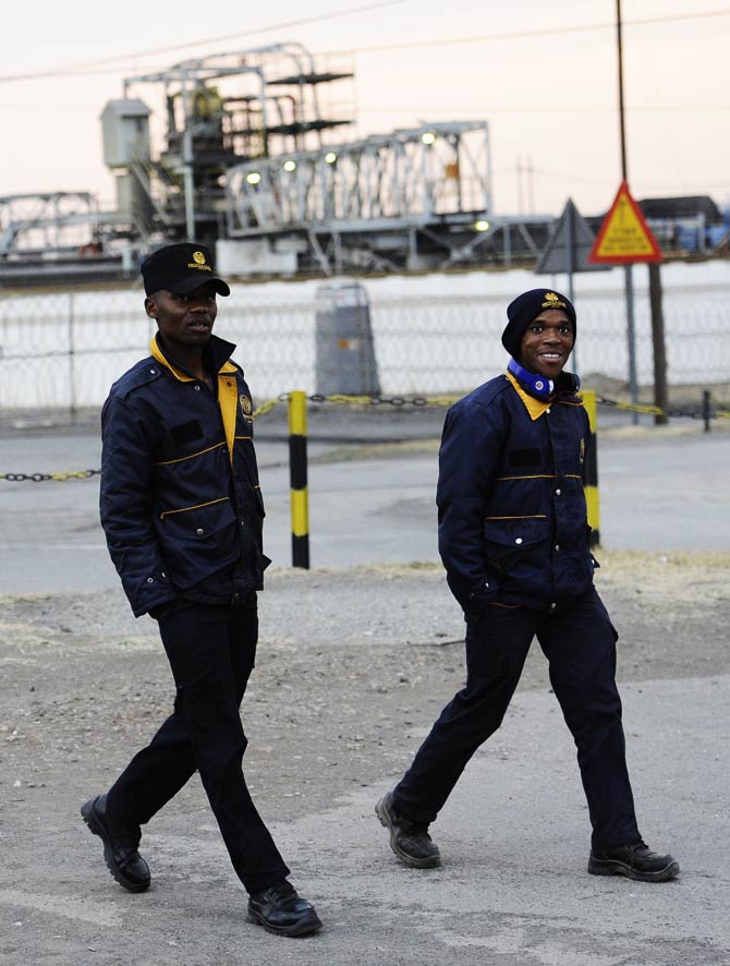 Two guards walk outside the Lonmin platinum mine in Marikana. – Photo by AFP