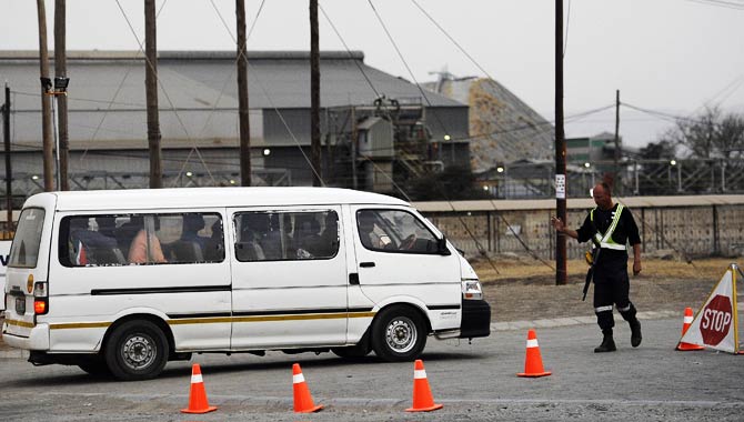 An armed private security guard controls the access at the main entrance of the Lonmin platinum mine. – Photo by AFP