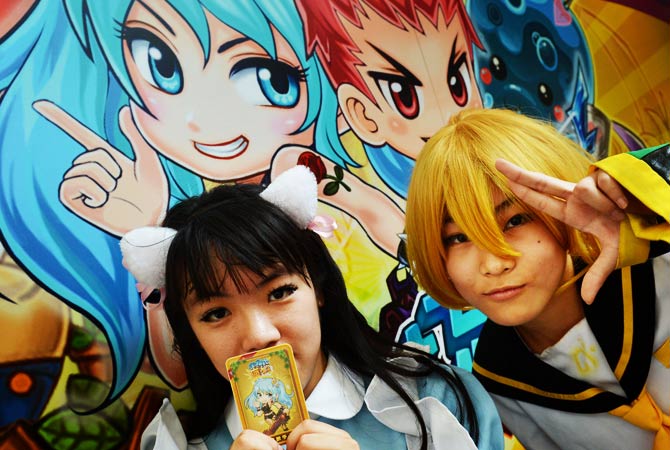 Two fans pose in front of a billboard. - Photo by AFP
