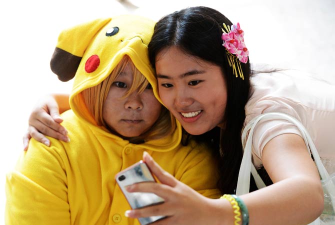 A cosplayer dressed as Pikachu poses with her friend for a picture. - Photo by AFP
