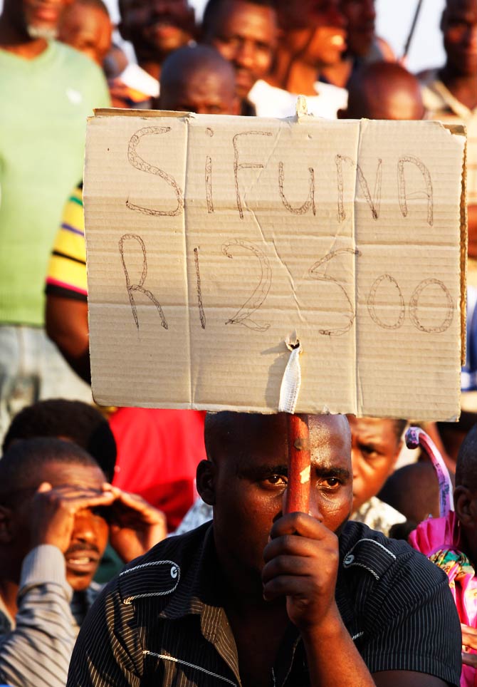An unidentified mine worker holds a placard that reads "we demand 12, 500 rands during their meeting at the Lonmin Platinum. – Photo by AP