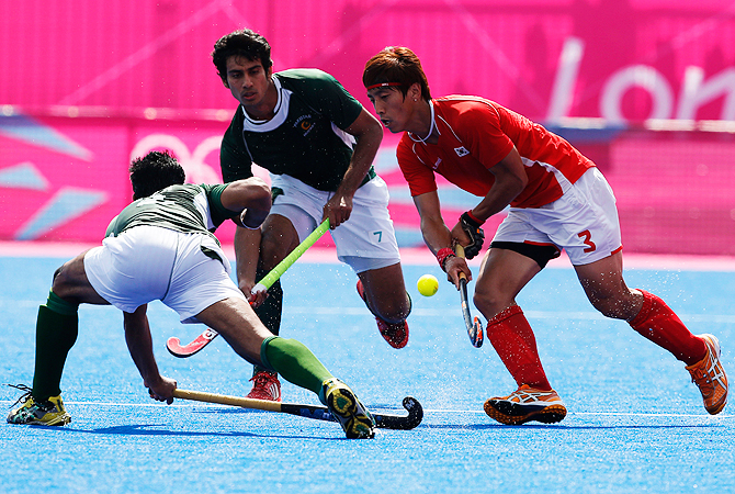 Pakistan's, Muhammed Irfan , left, and Korea's Jong-Hyun-jang, right, vie for the ball as Muhammad Waqas watches. -Photo by AP
