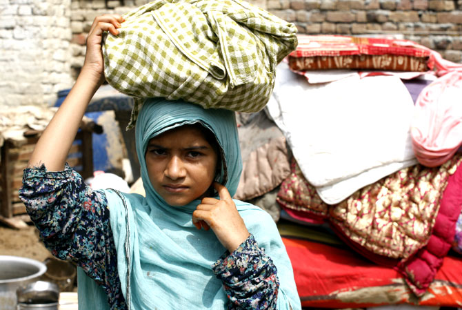 A flood-displaced girl carries her belongings in Nowshera, near Peshawar on Thursday, Aug. 23, 2012.