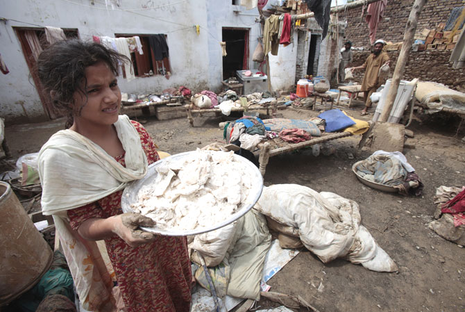 A girl carries flour spoiled by rain water.
