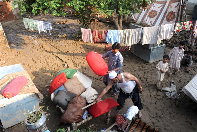 Residents place their belongings on a wooden bed after floodwaters inundated their house.