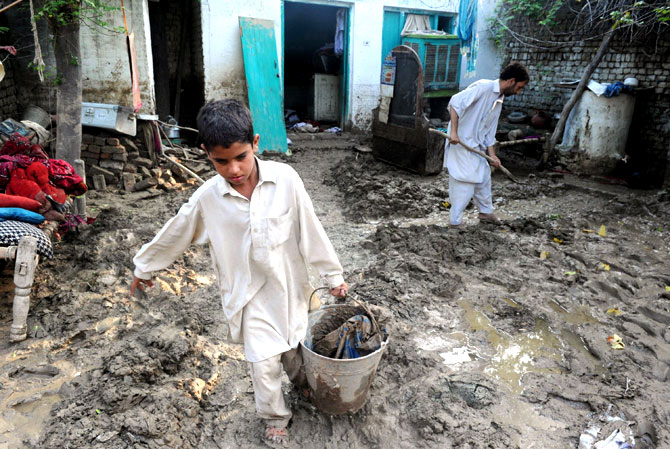 A resident and his son remove mud after floodwaters inundated his house.