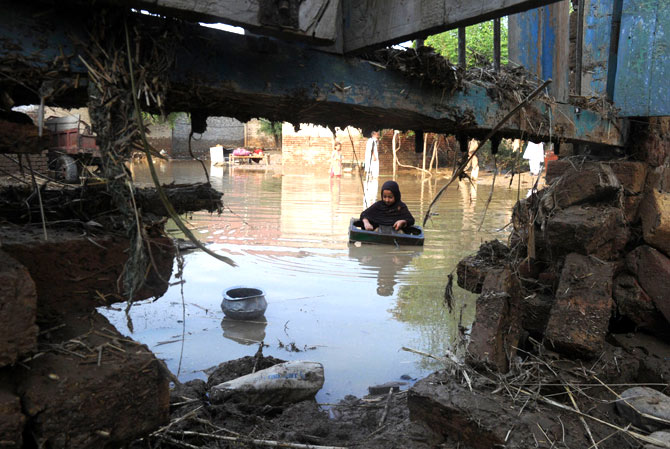 A girl carries a stovetop burner frame as she wades through floodwaters.