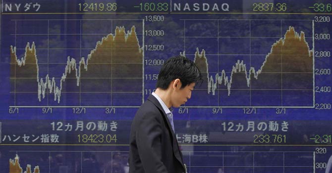 tokyo-stockscreen-670-reute A trader walking past a screen at Tokyo Stock Exchange — File Photo