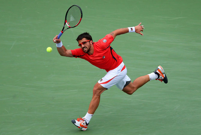 Janko Tipsarevic of Serbia returns a shot against David Ferrer of Spain during their men's singles quarterfinal match on Day Eleven of the 2012 US.