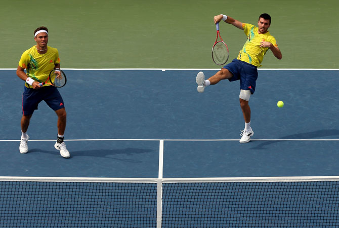 Colin Fleming smashes the ball next to his partner Ross Hutchins of Great Britain during their men's doubles third round match against Ryan Harrison and Christian Harrison of the United States on Day Seven of the 2012 US Open.