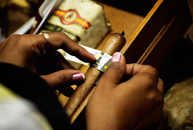 A woman fixes the ring on a cigar. ? Photo by Reuters