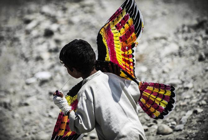 An Afghan child runs with a kite made by the French student association. ? Photo by AFP